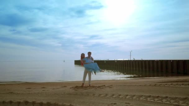 Чоловік, що носить дружину на руках на морському пляжі. Чоловік тримає вагітну дружину — стокове відео