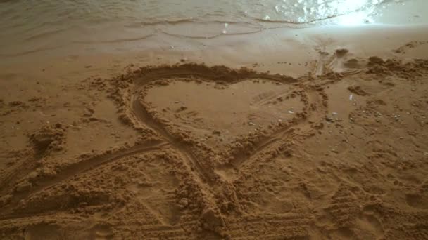 Forma de corazón en arena de playa. Un disparo firme. Corazón dibujar en playa de arena — Vídeos de Stock