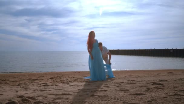 Kobieta w ciąży z niebieski tkaniny Latanie na plaży. Koncepcja ciąży — Wideo stockowe