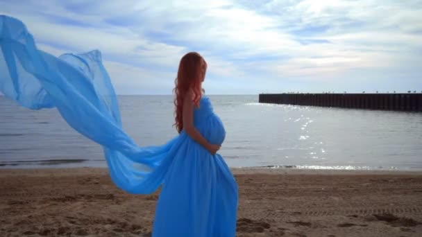 Rüzgarda uçan mavi elbiseli hamile kadın. Gebelik kavramı — Stok video