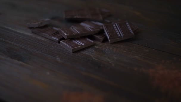 Barretta al cioccolato fondente. Cacao in polvere in tazza di vetro su fondo di legno — Video Stock