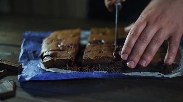 Man skivning tårta på träbord. Beredd choklad tårta bitar på kök — Stockvideo