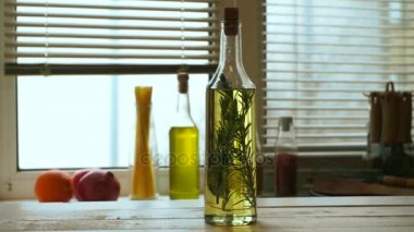 Zeytinyağı şişesi mutfak masasının üzerinde. Rosemary ile sızma zeytinyağı
