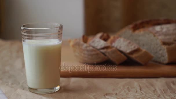 Vaso de leche y pan rebanado en la mesa de la cocina. Productos lácteos en el desayuno — Vídeos de Stock