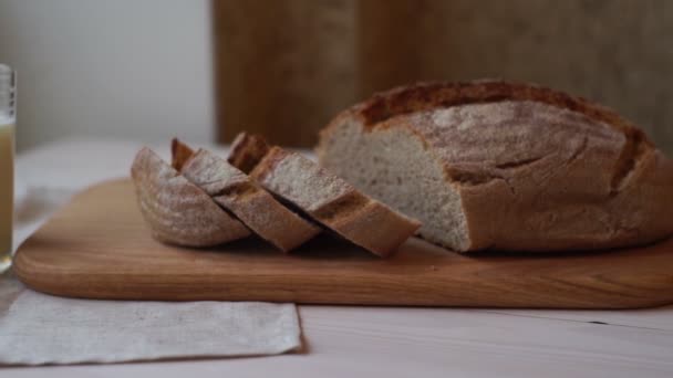 Pão de fatia na tábua de corte. Produto assado. Copo de leite na mesa. Comida de padaria — Vídeo de Stock