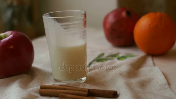 Verre de lait avec pomme rouge et orange sur la nappe. Alimentation petit déjeuner — Video