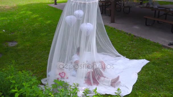 Couple tendre reposant derrière un voile blanc sur de l'herbe verte. Couple d'amour relax — Video