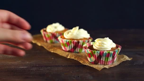 Vrouwelijke hand klaarmaaltijden cupcake op houten achtergrond. Zoete dessert — Stockvideo