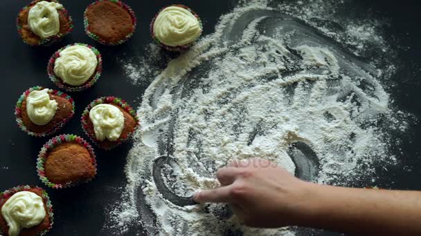 Felirat sütemények, fehér liszt kiömlött a konyhaasztalon. Sütés cupcake koncepció — Stock videók