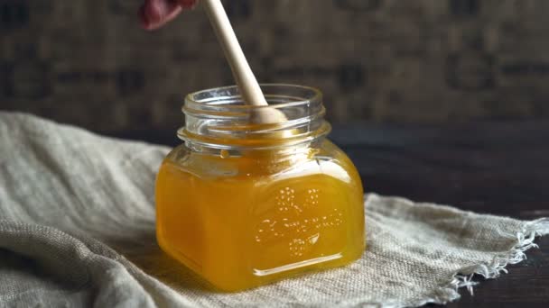 Honigglas mit Tropfer. Honigschale auf dem Tisch vorhanden. Honig tropft in Flasche — Stockvideo