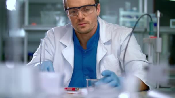 Ученый в лаборатории проводит медицинские исследования. Работник лаборатории наливает жидкость — стоковое видео
