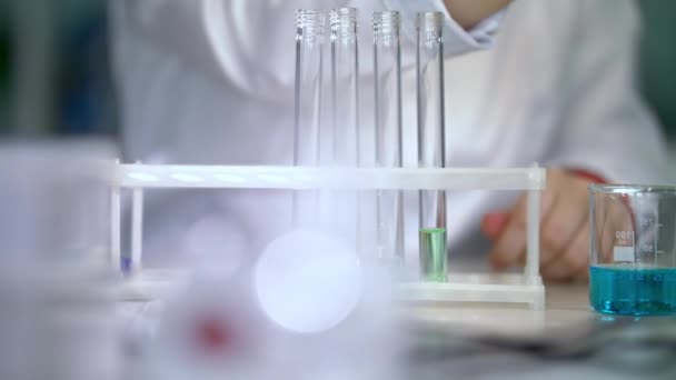 化学者は、ピペットでテーブルの上試験管で液体を置く — ストック動画