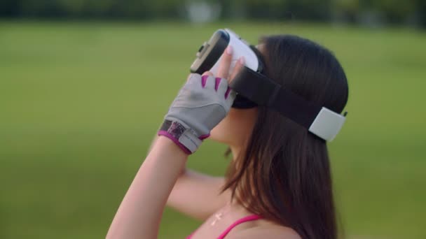 Азиатская женщина использует гарнитуру VR в парке. VR очки на голове женщины на открытом воздухе — стоковое видео