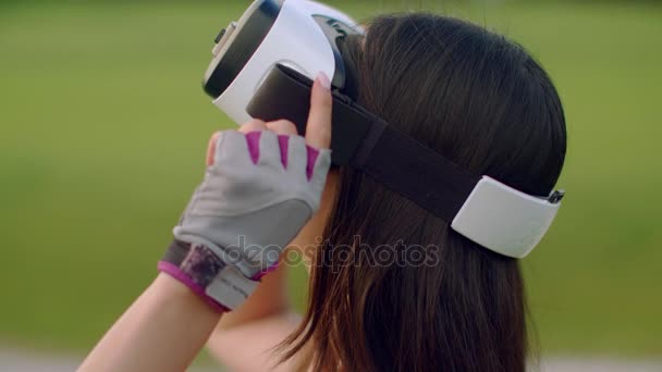 Mujer usando auriculares de realidad virtual en el parque. Mujer asiática con gafas VR — Vídeos de Stock