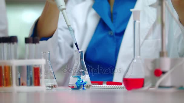 Female scientist pouring reagent in lab flask. Scientist doing chemical reaction — Stock Video