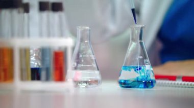 Cam şişe içinde kimyasal sıvı damlayan. Laboratuvar şişesi içinde kimyasal reaksiyon