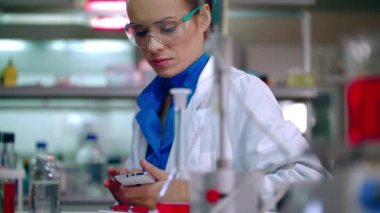 Kadın araştırmacı kaydırma telefon. Kadın araştırmacı laboratuarda akıllı telefon kullanma