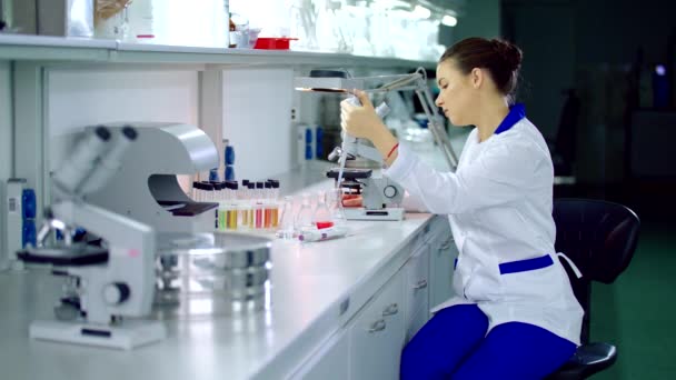 Mujer química investigando microscopios. Química femenina en laboratorio — Vídeo de stock