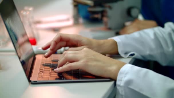 Científico escribiendo a mano en el portátil. Primer plano de la mujer científica manos en el ordenador portátil — Vídeos de Stock