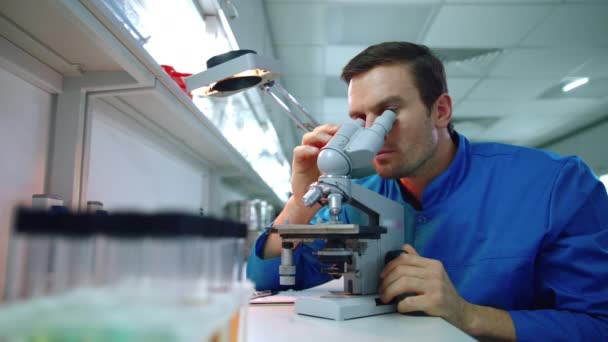 Kimyager kimya laboratuvar mikroskop kullanarak. Bilim adamı görünümlü mikroskop — Stok video