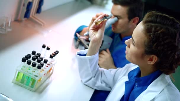 Grupo de cientistas a fazer pesquisa química. Cientista feminina estudando líquido — Vídeo de Stock