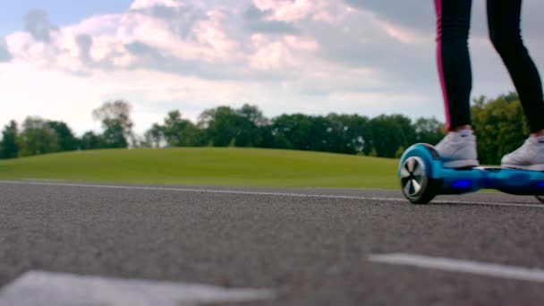 Frau fährt Gyroscooter auf Asphaltstraße am Park. Mädchen auf Elektro-Gyro-Roller — Stockvideo