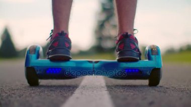 Adam asfalt yol, gyro scooter üzerinde hareket başlatın. Adam kendini denge hoverboard üzerinde