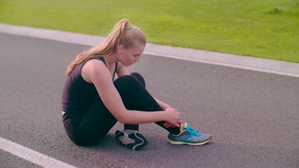 Mujer agotada sentada en camino de asfalto después de correr maratón — Vídeos de Stock