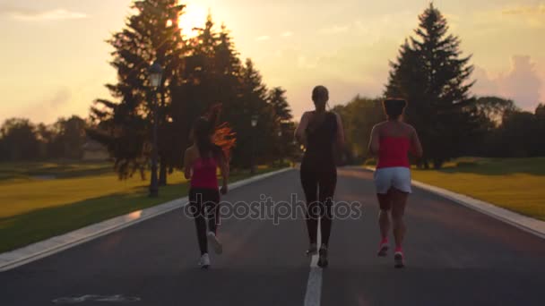 Futás-on sunset nők csoportja. Vissza view három fitness nő fut — Stock videók