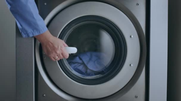 La mano femminile toglie vestiti di lavanderia. Primo piano della lavatrice industriale asciugatrice — Video Stock