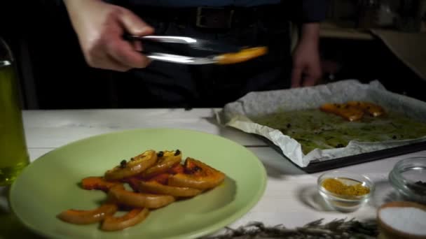 Рука шеф-повара кладет кусочки тыквы на тарелку. Жареная тыква — стоковое видео