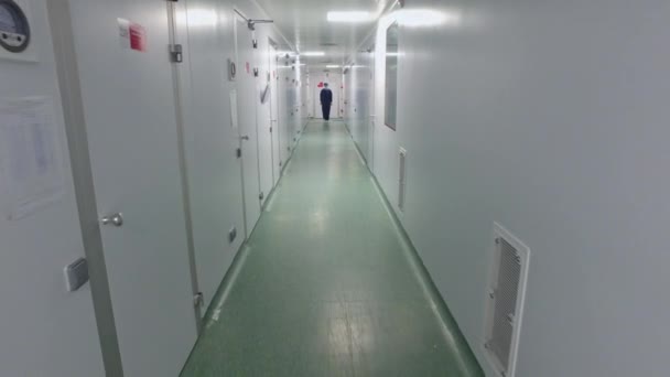 Прогулка по лабораторному коридору. Женщина-работница идет в химическую лабораторию — стоковое видео