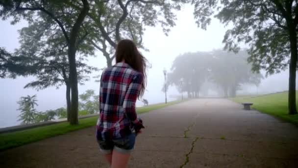 Mujer joven caminando en la niebla del parque. Caminante chica en árboles de niebla — Vídeo de stock
