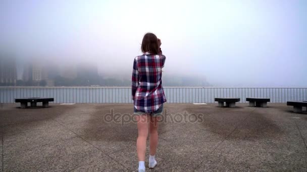 Mulher a olhar para o mar de nevoeiro. Mulher a olhar para a cidade do nevoeiro. Mulher em camisa casual — Vídeo de Stock