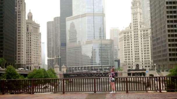 Feliz mujer sonriente de pie en el puente sobre el río en la gran ciudad — Vídeos de Stock