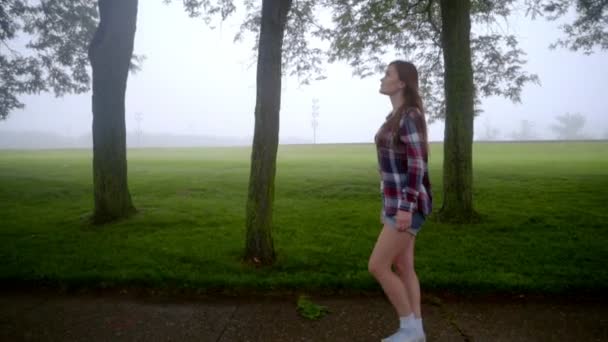 Mujer joven caminando en el parque. Vista de perfil de chica caminante — Vídeo de stock