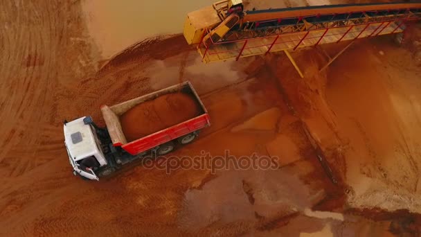 Горнодобывающий конвейер загружает песок в самосвал. Вид с воздуха на процесс добычи песка — стоковое видео