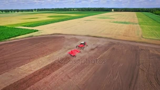 Agricultural tractor with trailer plowing ploughing field. Rural farming