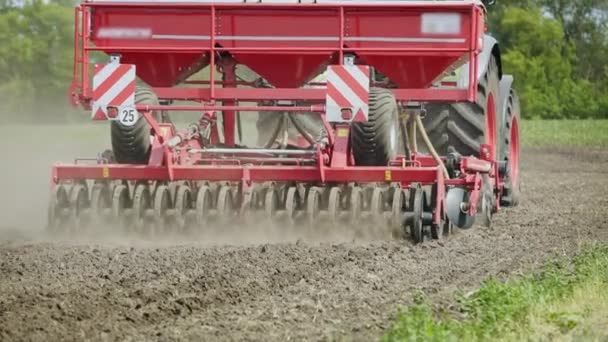 Ciągnika rolniczego z przyczepy siewnik pracę na zaorane pole. Obszarów wiejskich, rolnictwo — Wideo stockowe