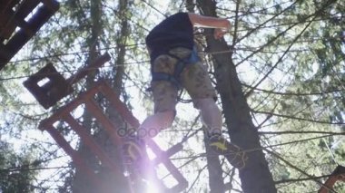 Güvenlik ekipmanları yüksek ip üzerinde park tırmanma yaz aylarında yürüyen genç adam