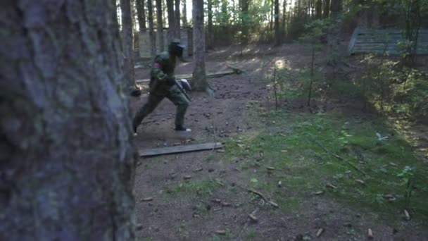 Пейнтболист, бегущий на поле боя во время стрельбы в летнем лесу — стоковое видео