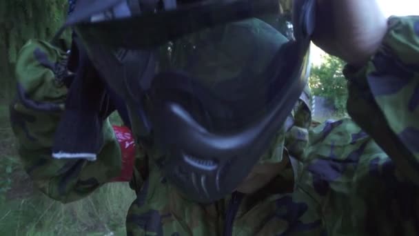 Молодий чоловік кладе маску для пейнтболу на голову перед зйомкою гри — стокове відео