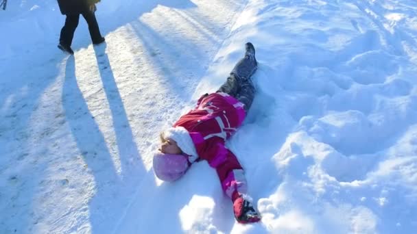 Lilla flickan liggande på snö. Sorglösa barn som leker i snö — Stockvideo