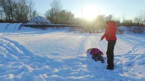 Zimní rodinný koncept. Matka a dcera se sněhovým radovánkám v pomalém pohybu — Stock video