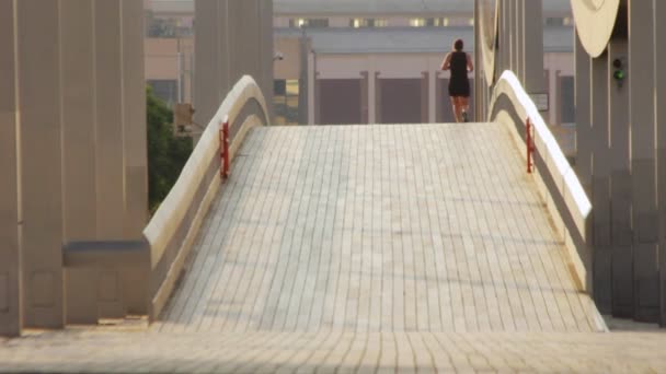 Donna in forma che corre attraverso ponte vista posteriore. Donna che fa jogging mattutino sul ponte — Video Stock