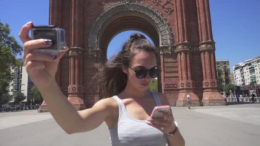 Kız yapma kendini bir eylem fotoğraf makinesinde video. Kadın turist Barcelona Arch yakınındaki