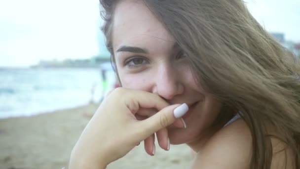 Retrato hermosa chica sentada en la playa. Mujer con el pelo ondulado en el viento — Vídeos de Stock