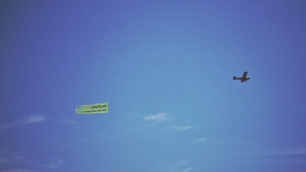 Single engine plane flying in the air. Small airplane towing advertisment banner — Stock Video