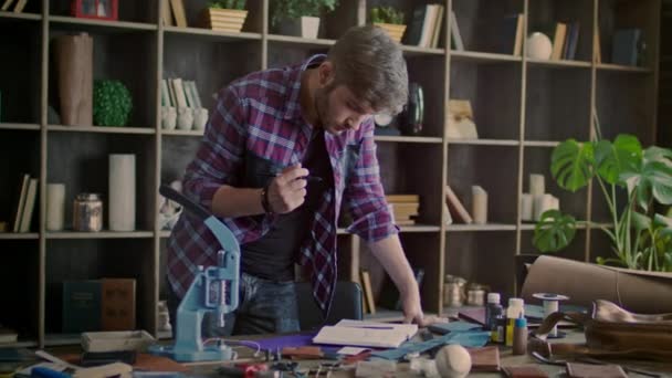 Produttore di pelle pensando a una nuova idea per il prodotto in pelle a casa workshop — Video Stock