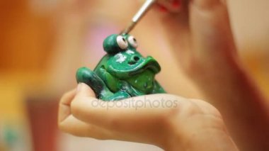 İş yerinde potter. Kadın portre resim yeşil seramik kurbağa eller